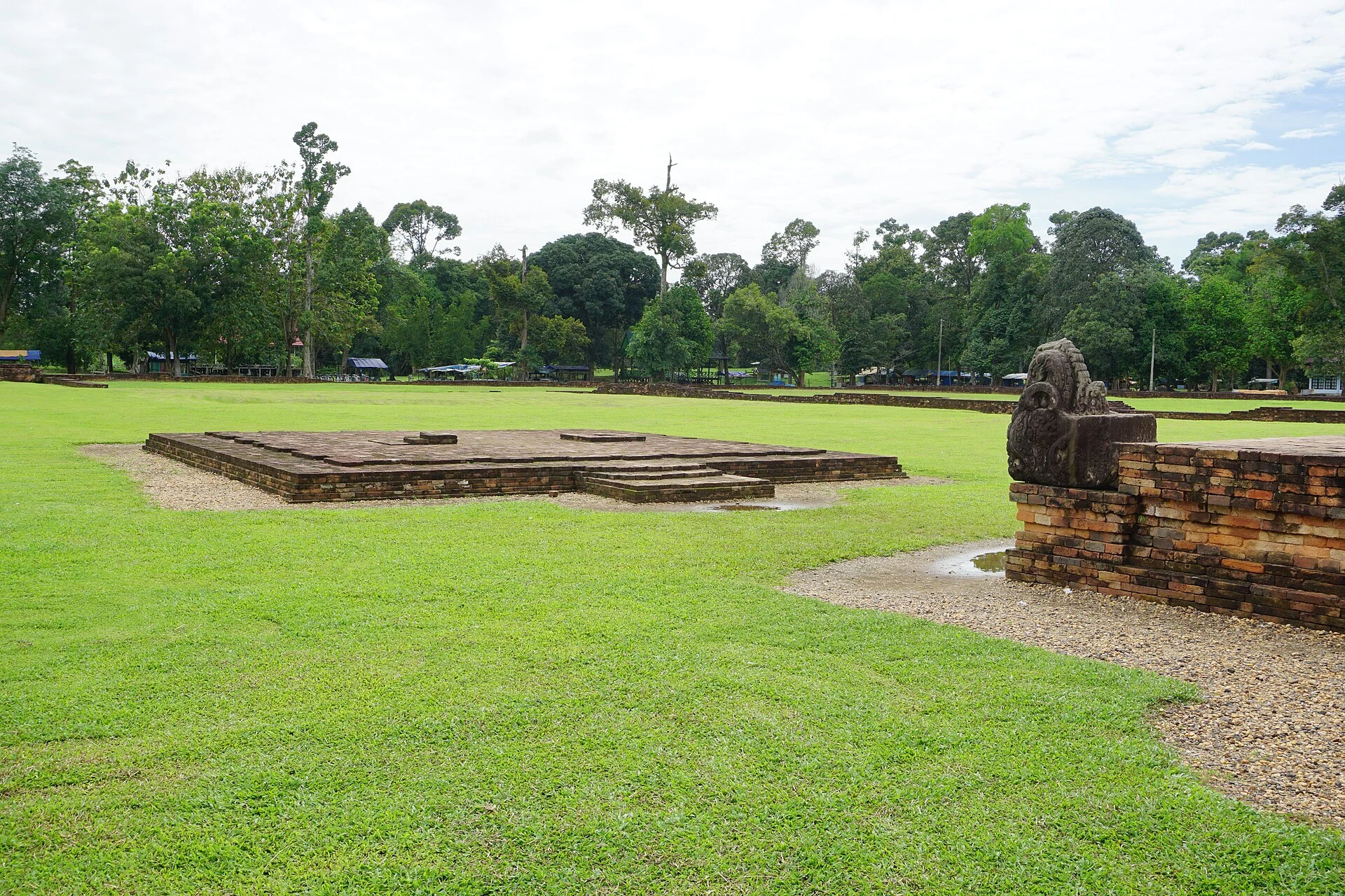 Estructura de ladrillo de Candi Gumpung entre hierba y árboles en Muara Jambi.