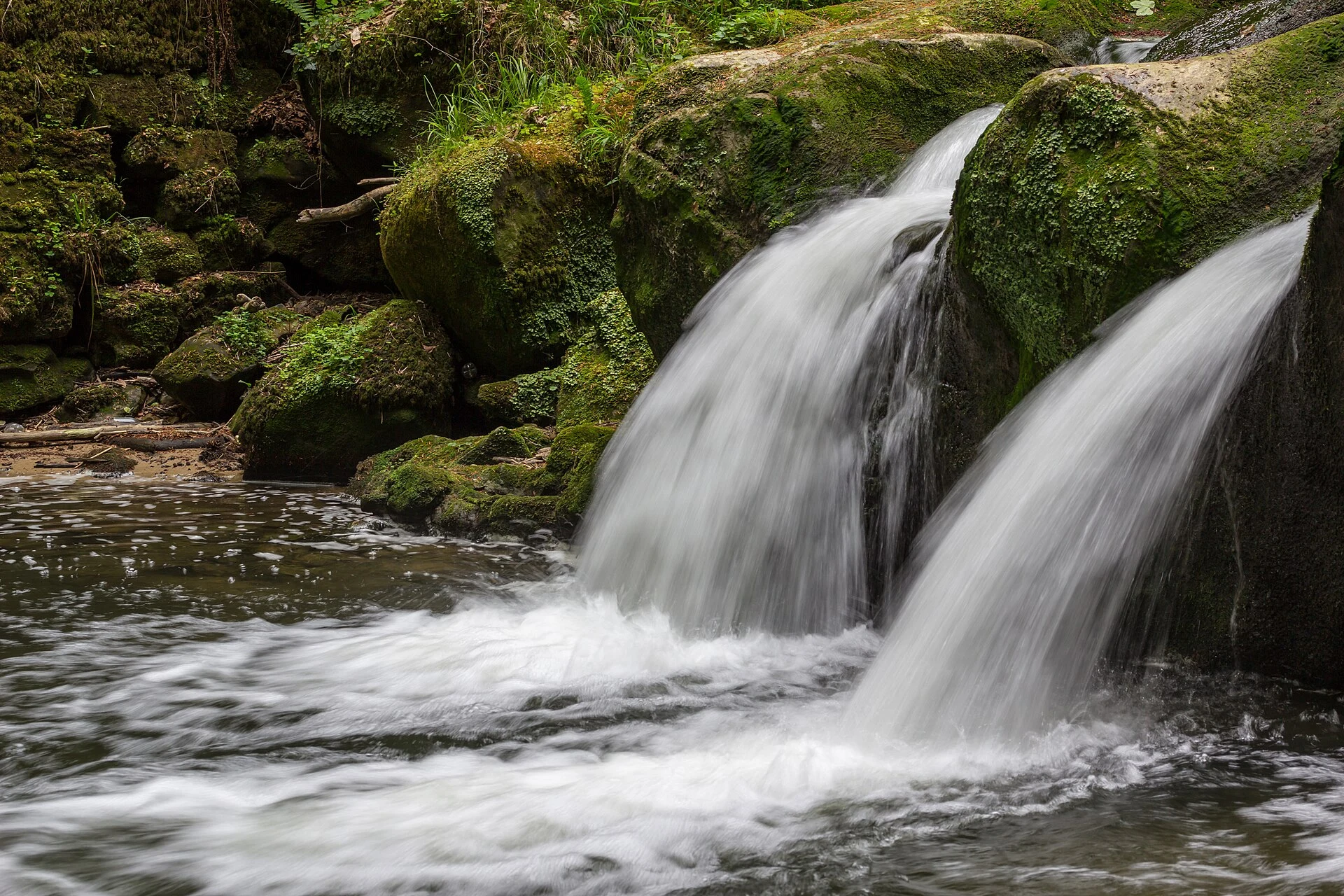 Cascada Schiessentümpel entre rocas y bosque en Müllerthal, Luxemburgo.