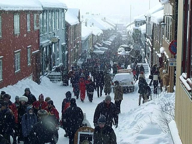 Casas de madera oscura junto a una calle nevada del centro histórico de Røros.