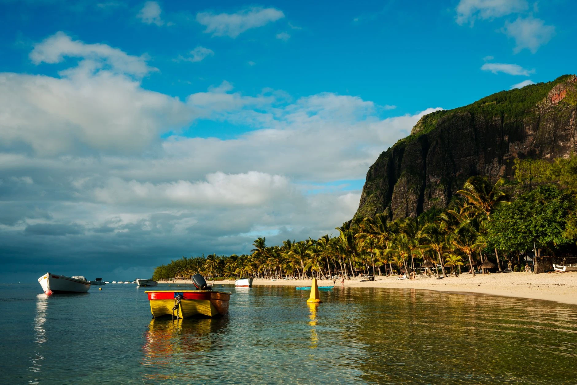 Playa con palmeras y embarcaciones en Le Morne, Mauricio.