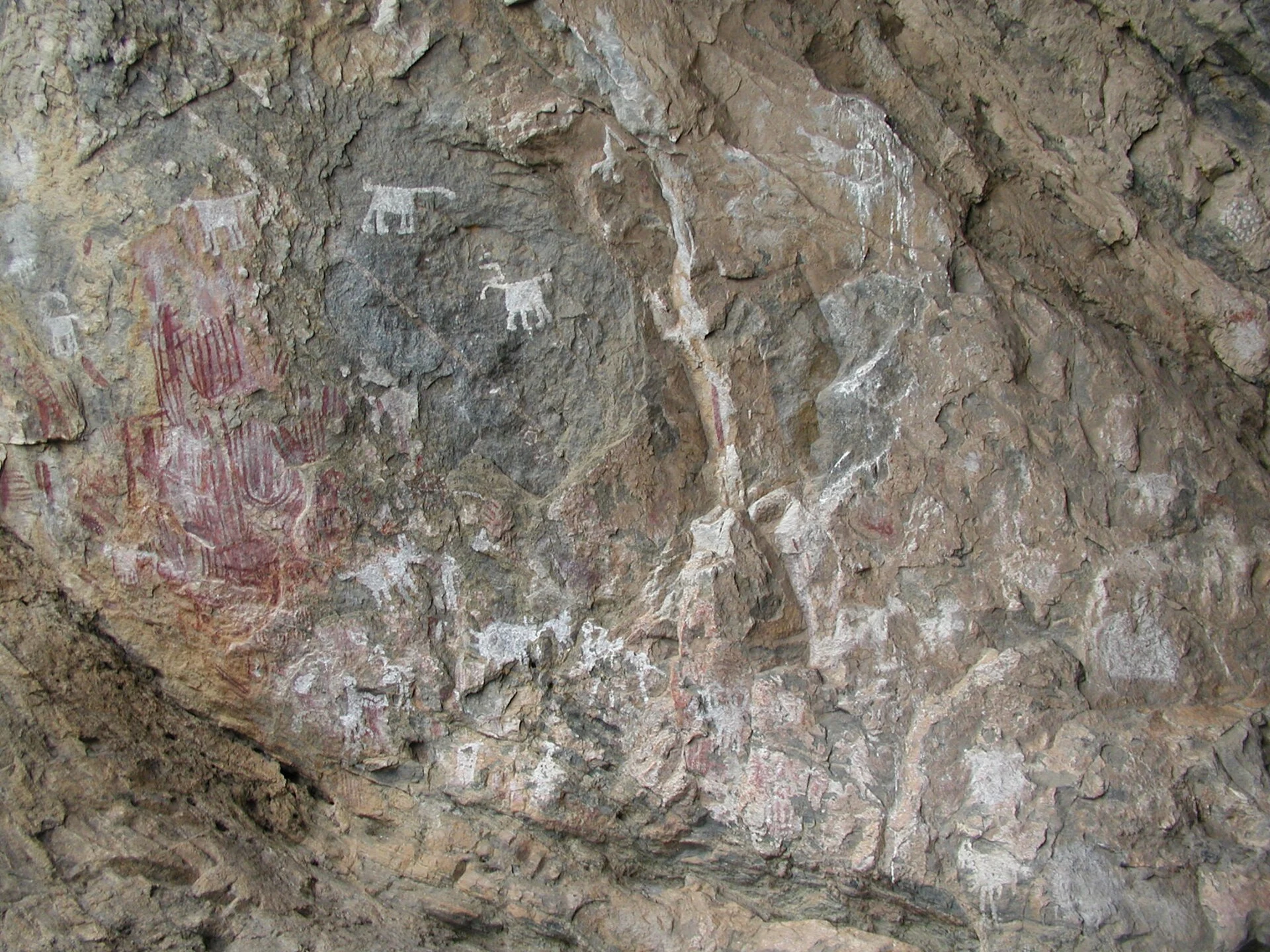 Detalle respetuoso de pinturas rupestres rojas y blancas sobre granito en Chongoni.