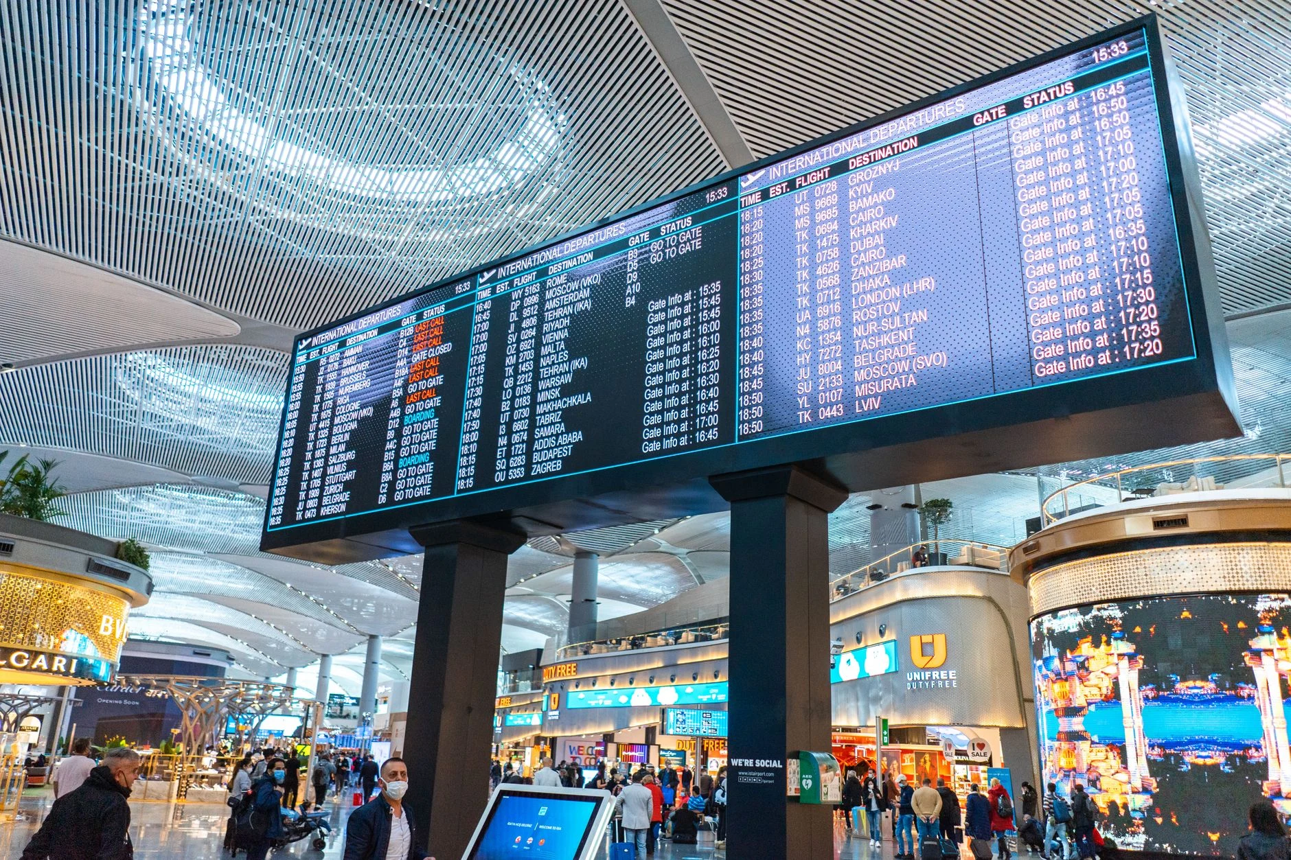 Una persona consulta información de vuelos en un aeropuerto; no se muestran horarios legibles.